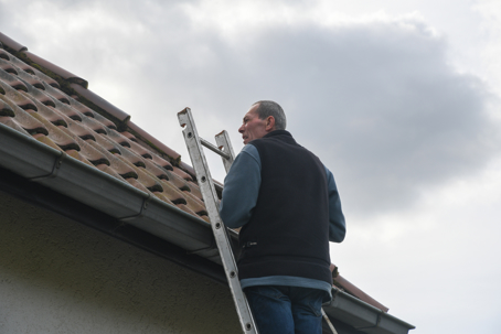 a man on a ladder checking the roof